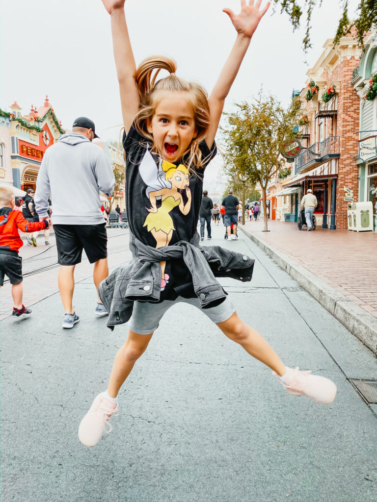 a kid jumping at Main Street in Disneyland Disneyland With Kids - 102 Tips You Need To Know