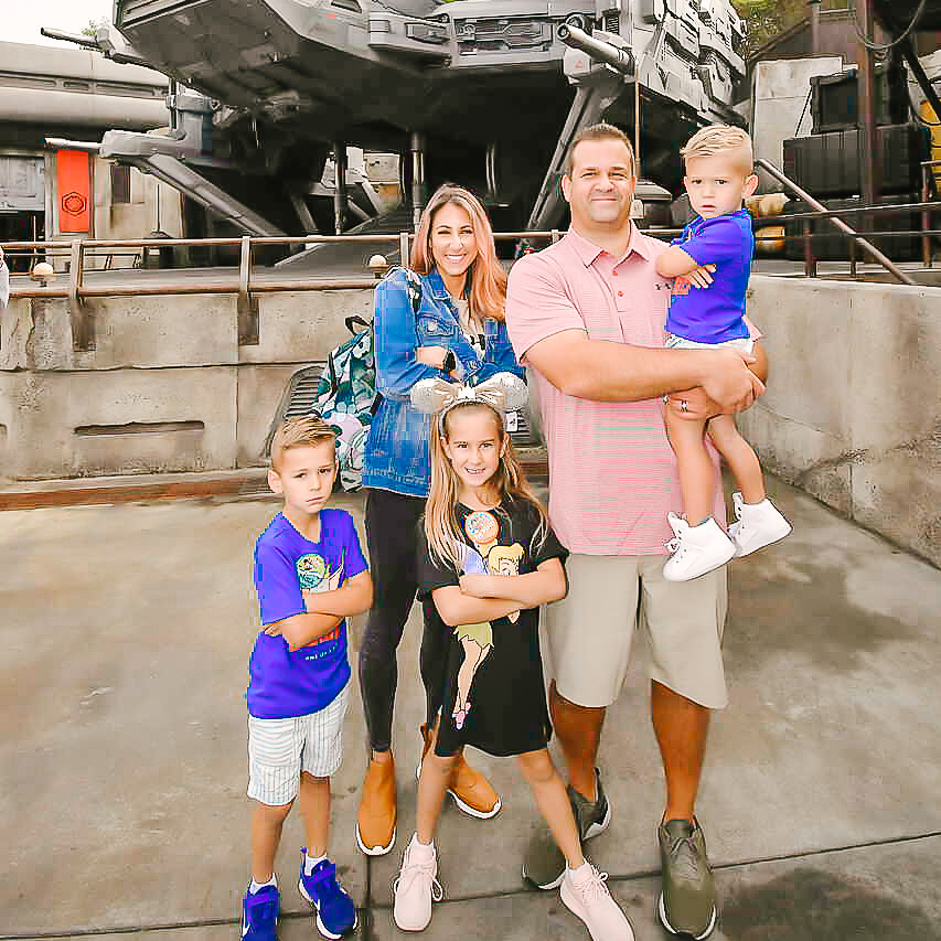 family taking a picture in front of the Millennium Falcon at Disneyland 
